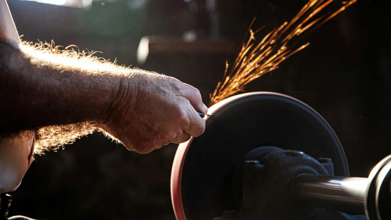 A craftsman sharpening a blade on a grinding wheel